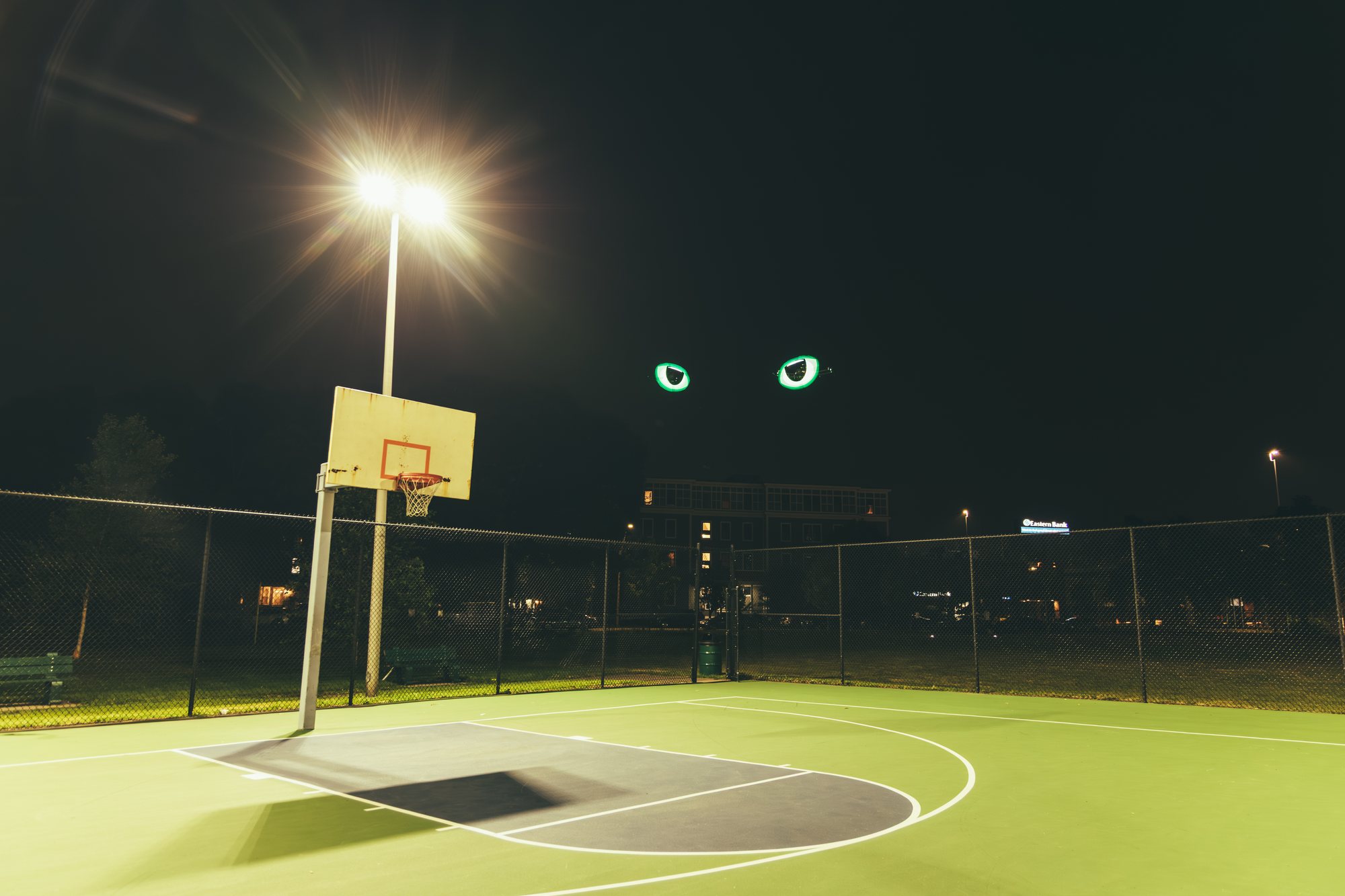 Two Canvair drones rendering glowing eyes above a basketball court at night
